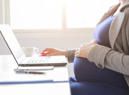 pregnant woman is working on computer laptop - pregnant workers fairness act concept