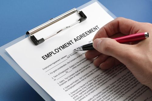 Man filling out an employment agreement contract - types of employment contracts concept