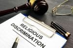 Religious Discrimination claim clipped to a clipboard and pen on a table - religious discrimination in the workplace concept